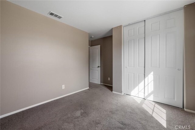 unfurnished bedroom with a closet, baseboards, visible vents, and carpet floors