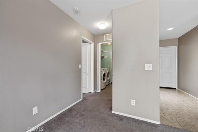 corridor featuring carpet, baseboards, visible vents, and washer and clothes dryer