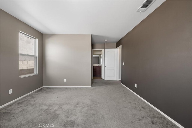 carpeted spare room featuring visible vents and baseboards