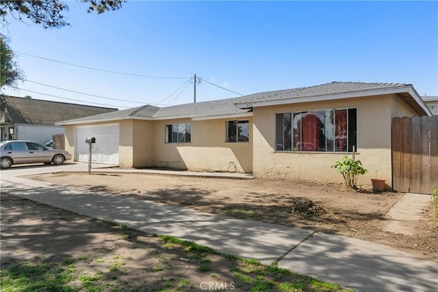 single story home featuring a garage, fence, concrete driveway, and stucco siding