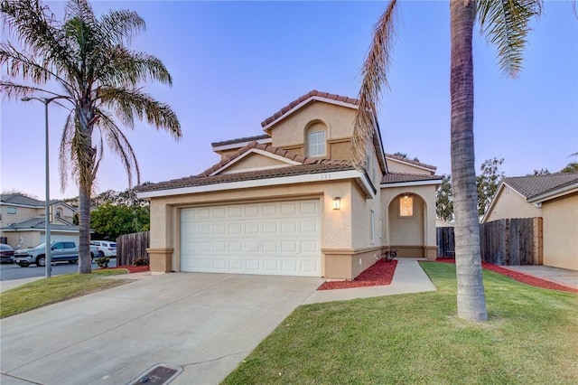 mediterranean / spanish house with fence, stucco siding, concrete driveway, a front lawn, and a garage