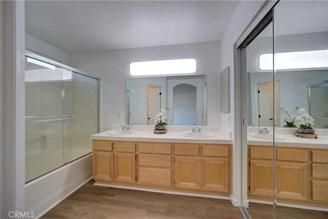 full bath featuring double vanity, wood finished floors, and a sink