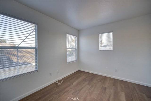 spare room with baseboards, a healthy amount of sunlight, and wood finished floors