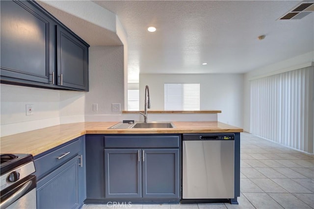 kitchen with visible vents, a peninsula, a sink, stainless steel appliances, and butcher block counters