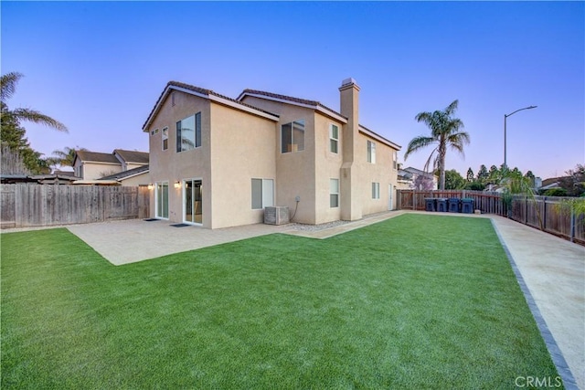 rear view of house featuring stucco siding, a patio, a lawn, and a fenced backyard