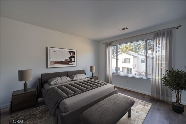 bedroom with visible vents, baseboards, and wood finished floors