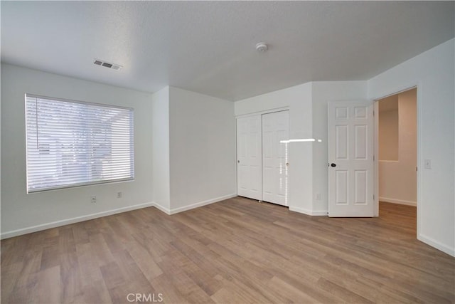 unfurnished room with baseboards, a textured ceiling, and light wood-style flooring