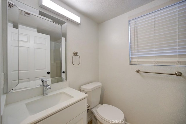 bathroom featuring vanity, toilet, visible vents, and a textured ceiling