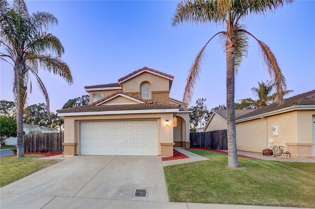 mediterranean / spanish-style home featuring stucco siding, concrete driveway, a front lawn, and fence