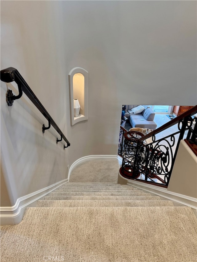 staircase featuring baseboards and carpet flooring