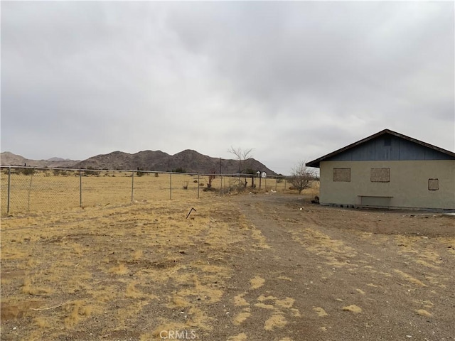 view of yard featuring a rural view, fence, and a mountain view