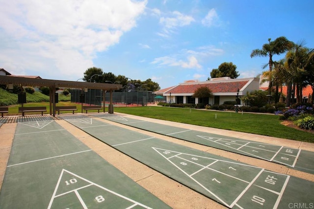 view of community with shuffleboard, a yard, and fence