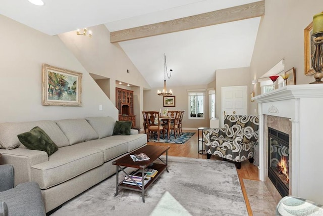 living area with beamed ceiling, a fireplace with flush hearth, high vaulted ceiling, light wood-style flooring, and an inviting chandelier