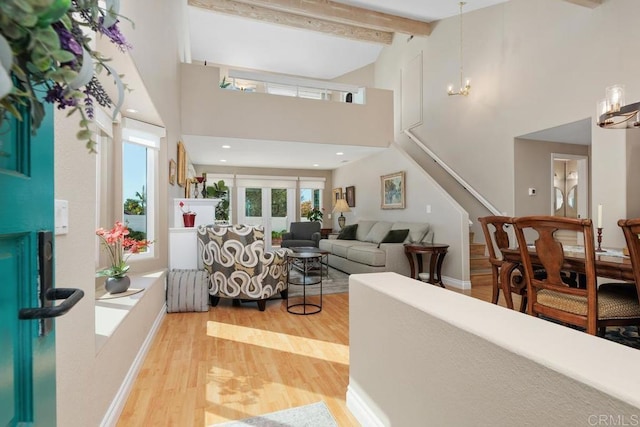 living room featuring high vaulted ceiling, an inviting chandelier, light wood-style flooring, stairs, and beamed ceiling