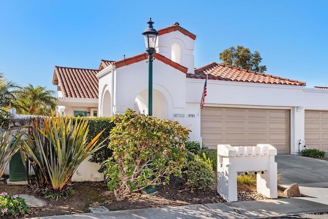 view of front facade with stucco siding, driveway, an attached garage, and a tile roof