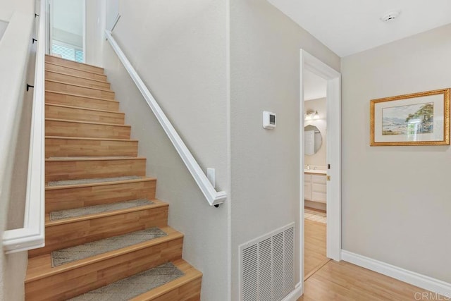 staircase featuring visible vents, baseboards, and wood finished floors