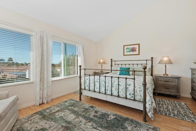 bedroom featuring wood finished floors, baseboards, and vaulted ceiling