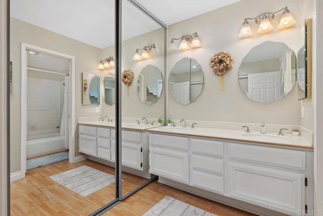 bathroom featuring double vanity, wood finished floors, shower / bath combo, and a sink