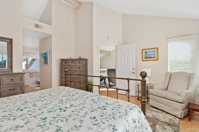 bedroom with visible vents, high vaulted ceiling, ensuite bathroom, and wood finished floors