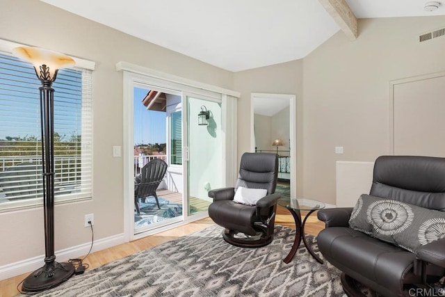 sitting room with lofted ceiling with beams, wood finished floors, visible vents, and baseboards