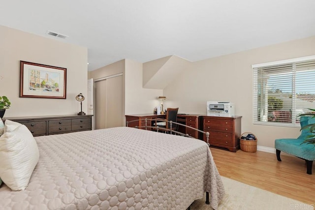 bedroom featuring a closet, visible vents, baseboards, and wood finished floors