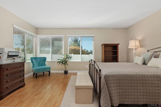 bedroom featuring light wood-style flooring, baseboards, and multiple windows