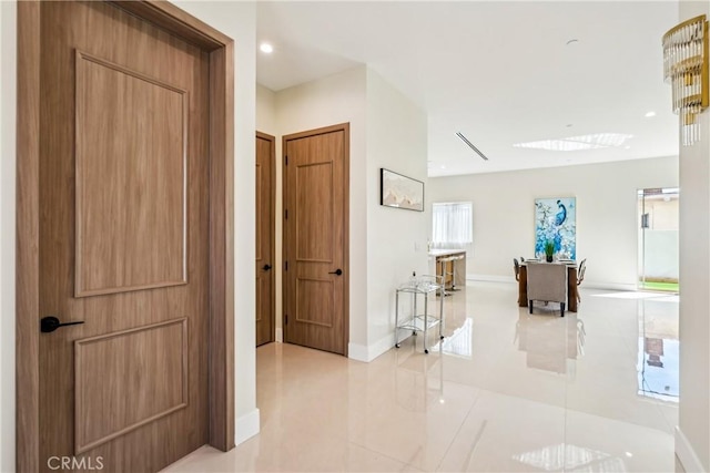 hallway with recessed lighting, light tile patterned floors, and baseboards