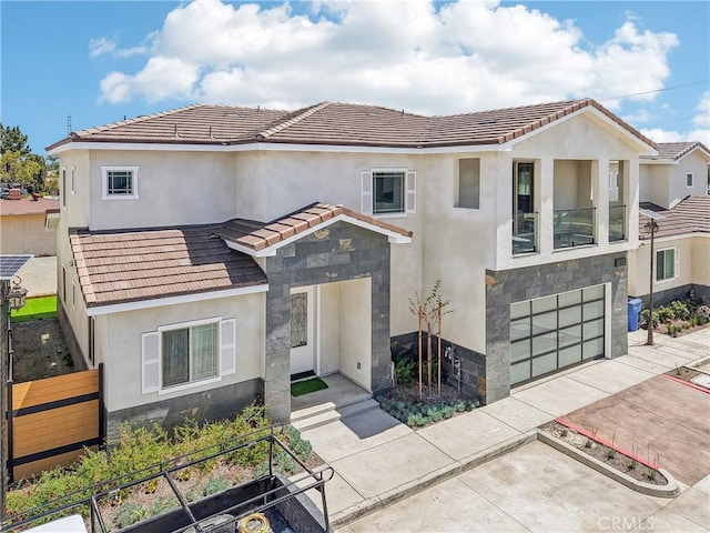 mediterranean / spanish home with a tiled roof, an attached garage, driveway, and stucco siding