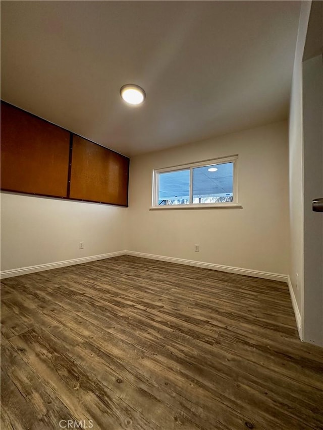 unfurnished room with baseboards and dark wood-style floors