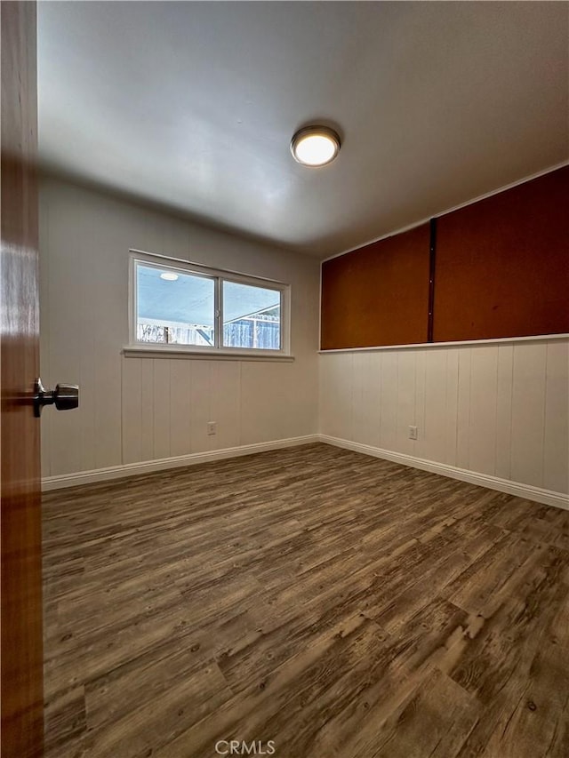 empty room with baseboards and dark wood-style flooring