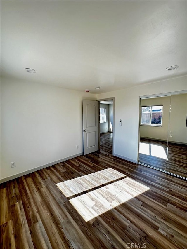 spare room with baseboards and wood finished floors