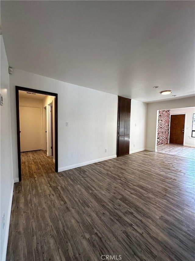 unfurnished living room featuring baseboards and dark wood finished floors