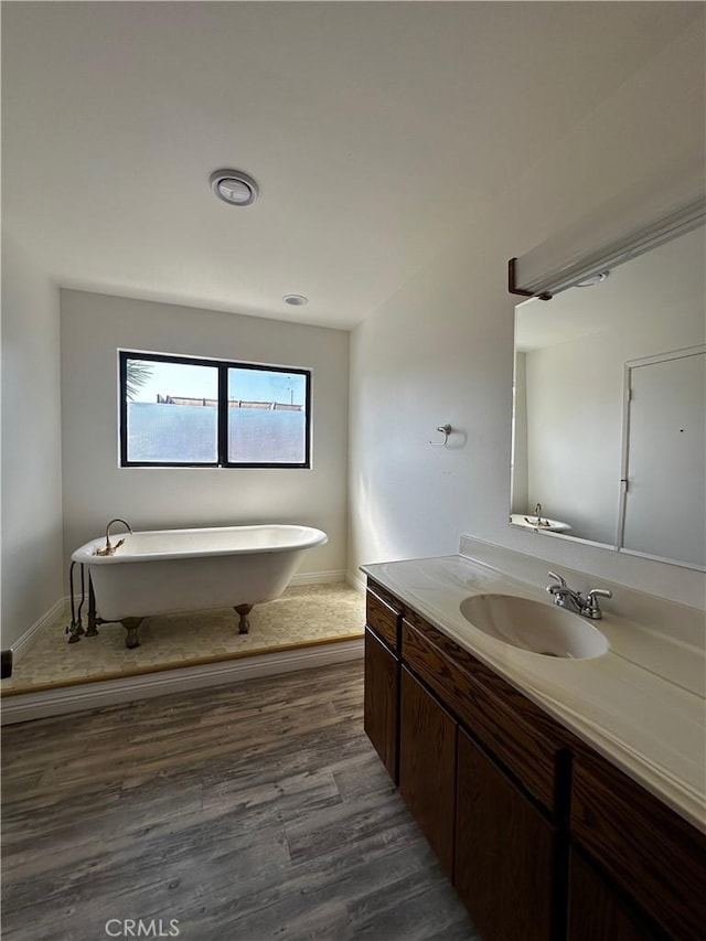 full bath featuring a freestanding tub, vanity, and wood finished floors