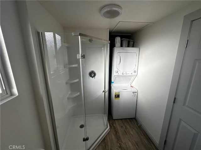 bathroom with stacked washer / drying machine, baseboards, wood finished floors, and a shower stall