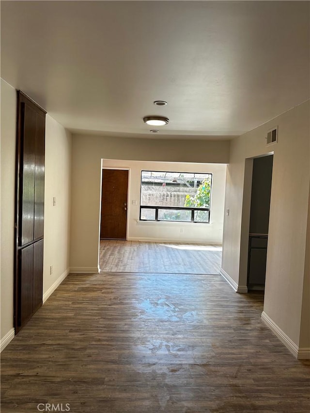 interior space featuring visible vents, dark wood-type flooring, and baseboards