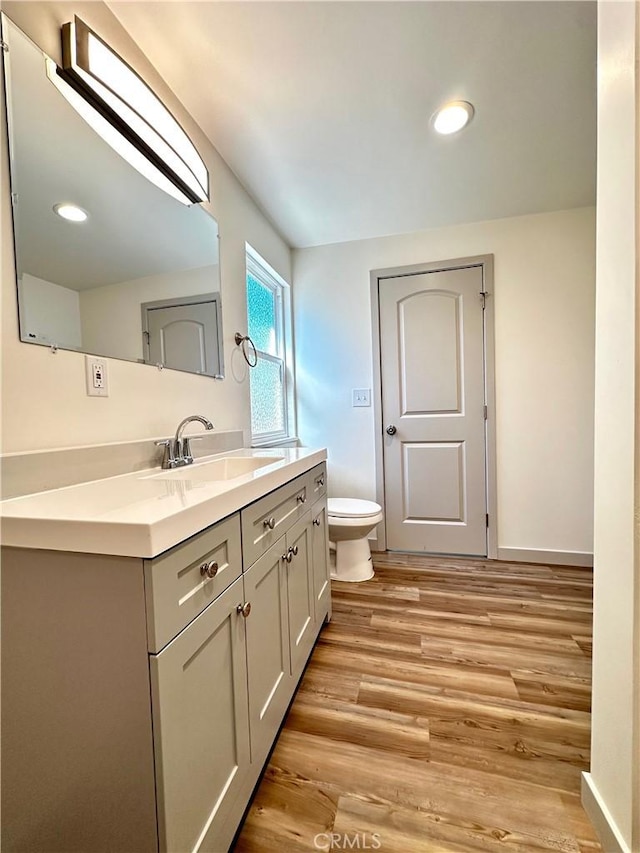 bathroom featuring toilet, vanity, baseboards, and wood finished floors