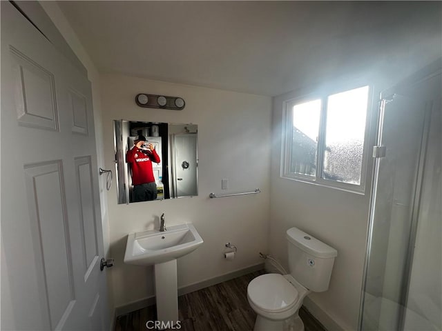 full bathroom with wood finished floors, baseboards, toilet, and a stall shower