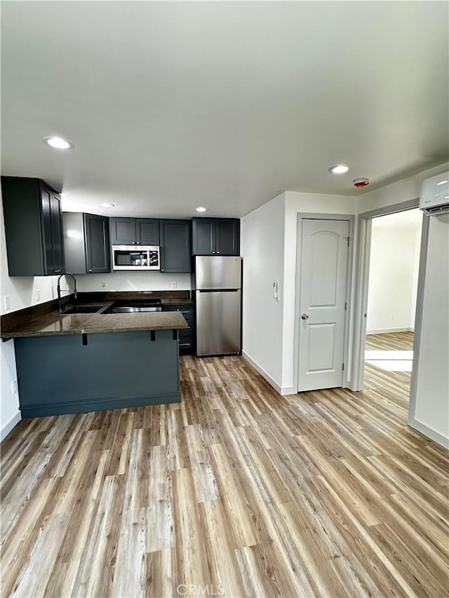 kitchen featuring a sink, dark countertops, a peninsula, and stainless steel appliances