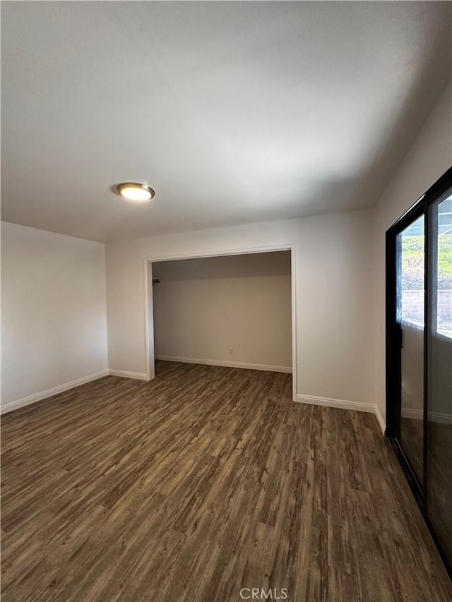 unfurnished bedroom with dark wood-type flooring and baseboards