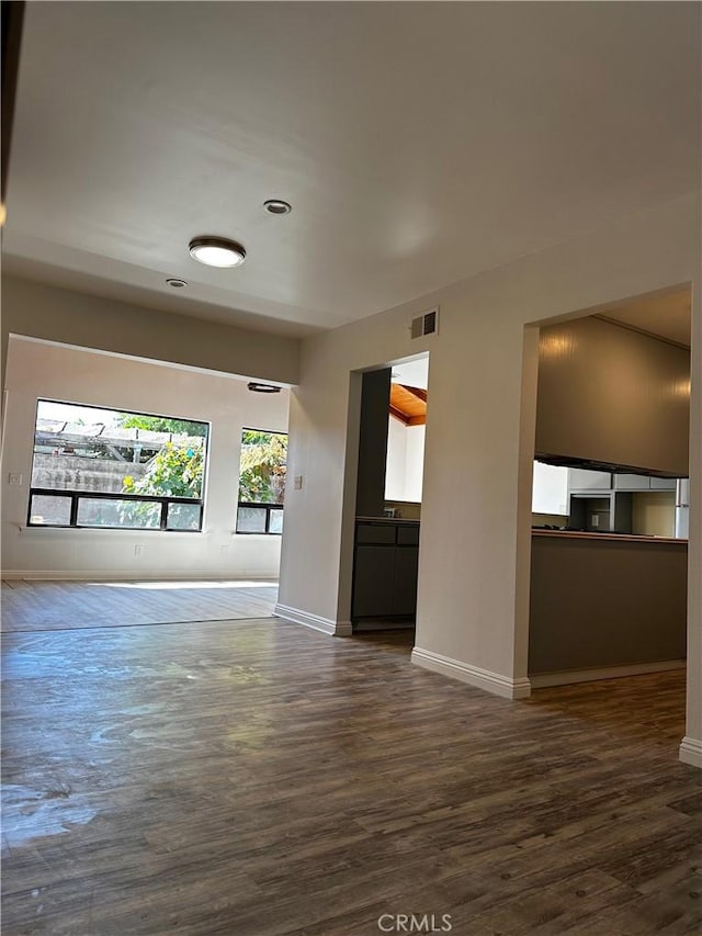 unfurnished room with visible vents, baseboards, and dark wood-type flooring