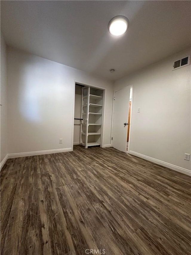 unfurnished bedroom with visible vents, baseboards, a closet, and dark wood-style flooring