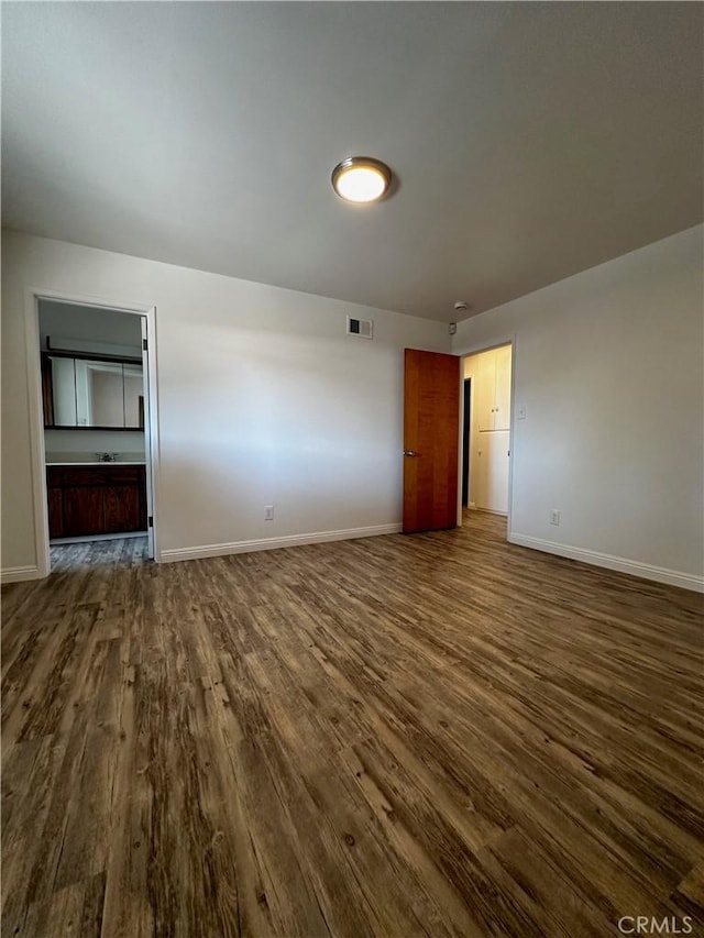 unfurnished living room featuring dark wood-type flooring, baseboards, and visible vents