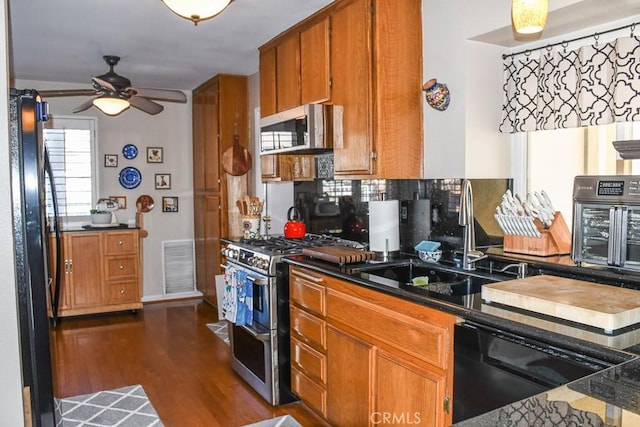 kitchen with visible vents, dark wood-type flooring, brown cabinetry, black appliances, and a sink