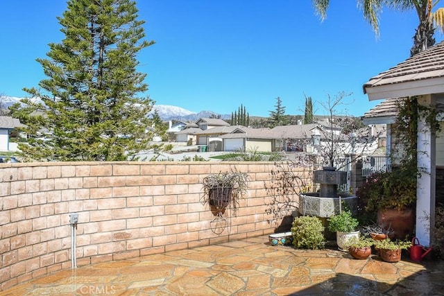 view of patio / terrace with fence, a mountain view, and a residential view