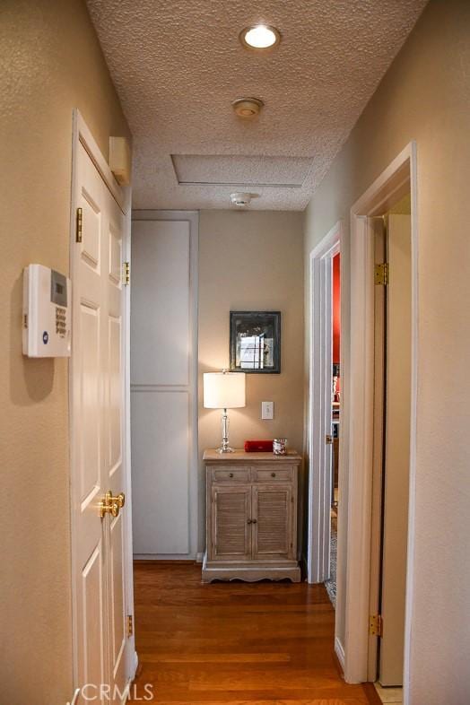 hall with a textured ceiling and wood finished floors