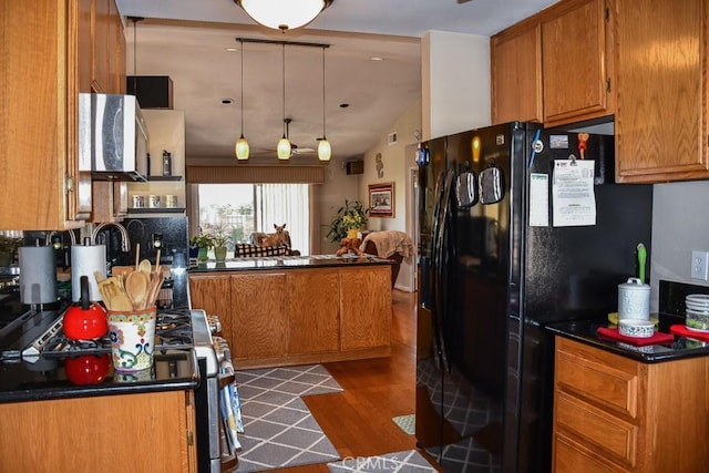 kitchen with brown cabinets, dark countertops, dark wood-style floors, and freestanding refrigerator