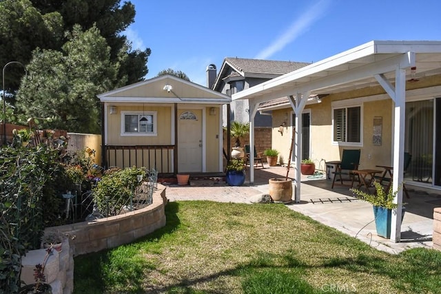 back of house with an outdoor structure, a yard, fence, and a patio area