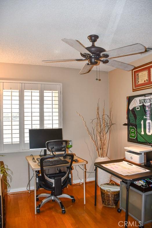 office space featuring baseboards, a textured ceiling, ceiling fan, and wood finished floors