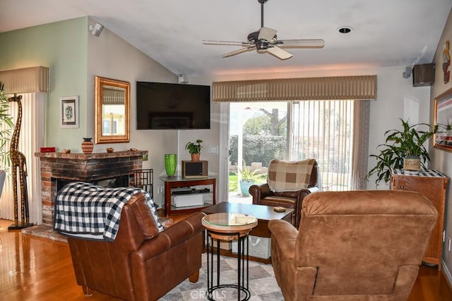 living room with lofted ceiling, a brick fireplace, wood finished floors, and a ceiling fan