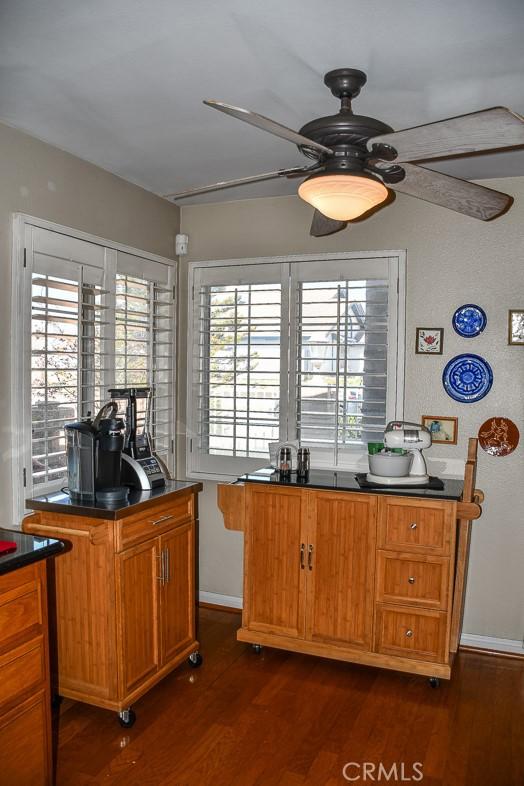 kitchen with dark wood-style floors, baseboards, ceiling fan, dark countertops, and brown cabinets